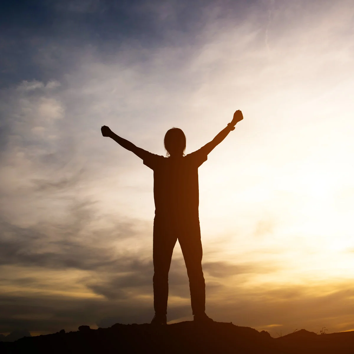 Persona en una cima con los brazos extendidos